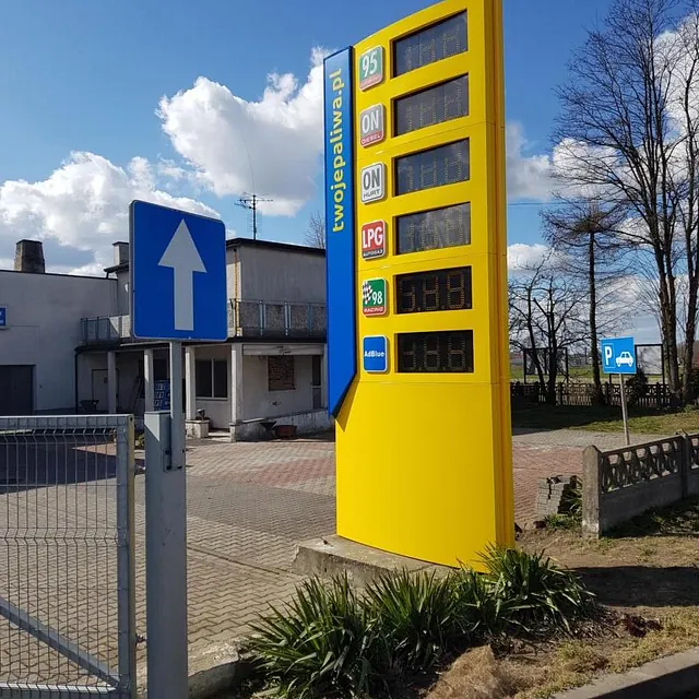Żółty pylon cenowy przy stacji paliw